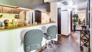 Une cuisine moderne avec un coin bar, deux tabourets de bar et une vue sur la salle à manger.