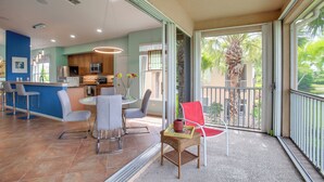A modern kitchen with a dining area, a balcony with a view of palm trees, and a bar area with bar stools. - 3 Mi to Dtwn Fort Myers: Condo w/ Pool & Hot Tub (North Fort Myers)