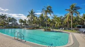 A swimming pool with a 4 ft 9 in depth marker, surrounded by palm trees and lounge chairs. - 3 Mi to Dtwn Fort Myers: Condo w/ Pool & Hot Tub (North Fort Myers)