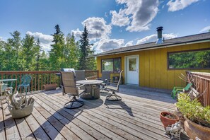 A wooden deck with outdoor furniture, a yellow building, and a chimney.