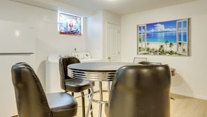 A dining area with a round table and four black chairs, a white door, a stained glass window, and a beach scene painting on the wall. - 5 Mi to Trilith Studios: Apt w/ Furnished Pergola (Fayetteville)