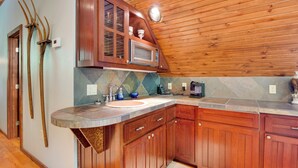 Cocina con armarios de madera, microondas y lavaplatos.