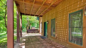 Un porche de madera con techo, una banca, una puerta y una ventana.