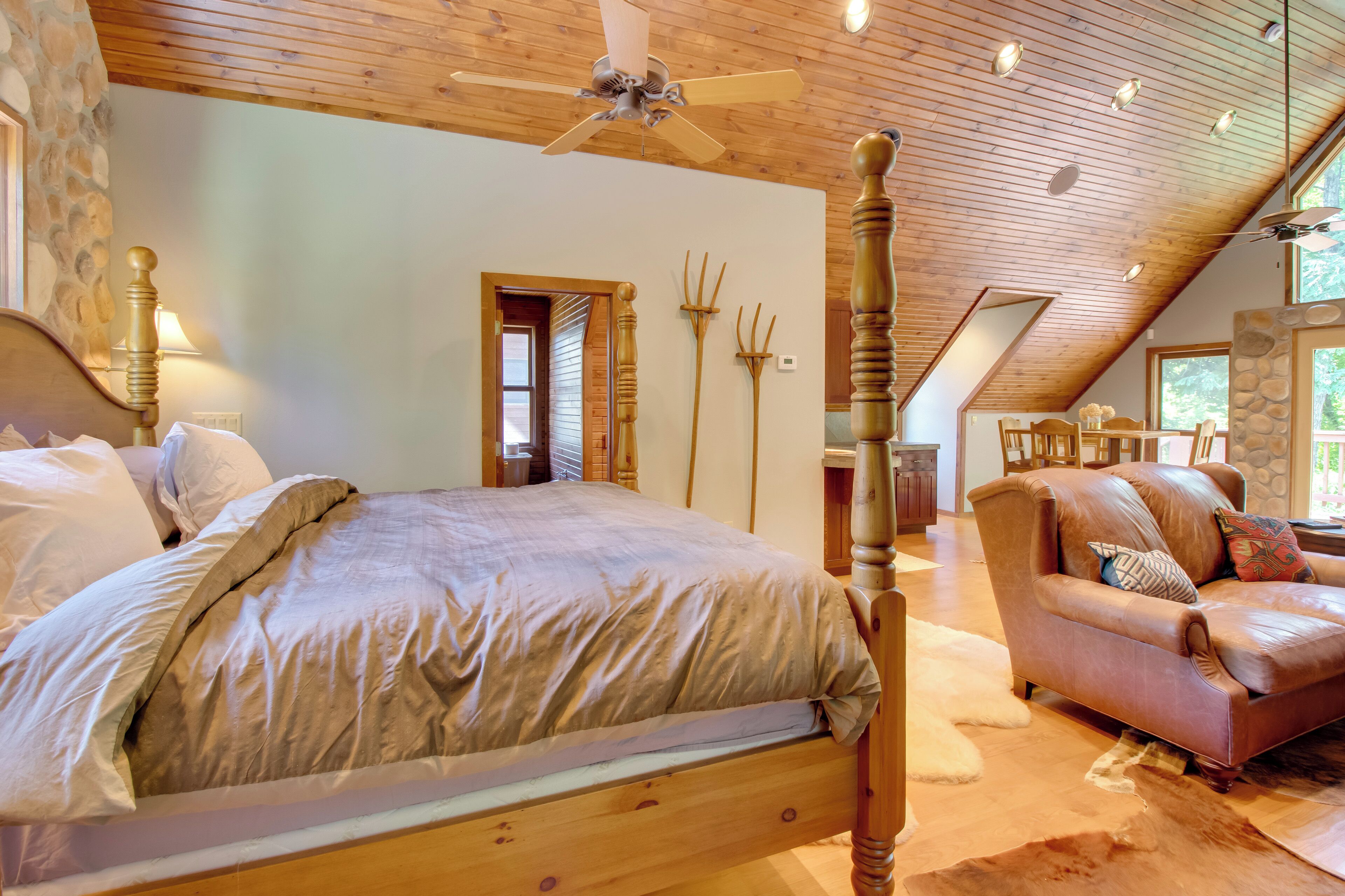 Een slaapkamer met een houten bed, een leren bank en een stenen openhaard.