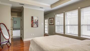 A bedroom with a large bed, a door leading to a bathroom, and a window with blinds.