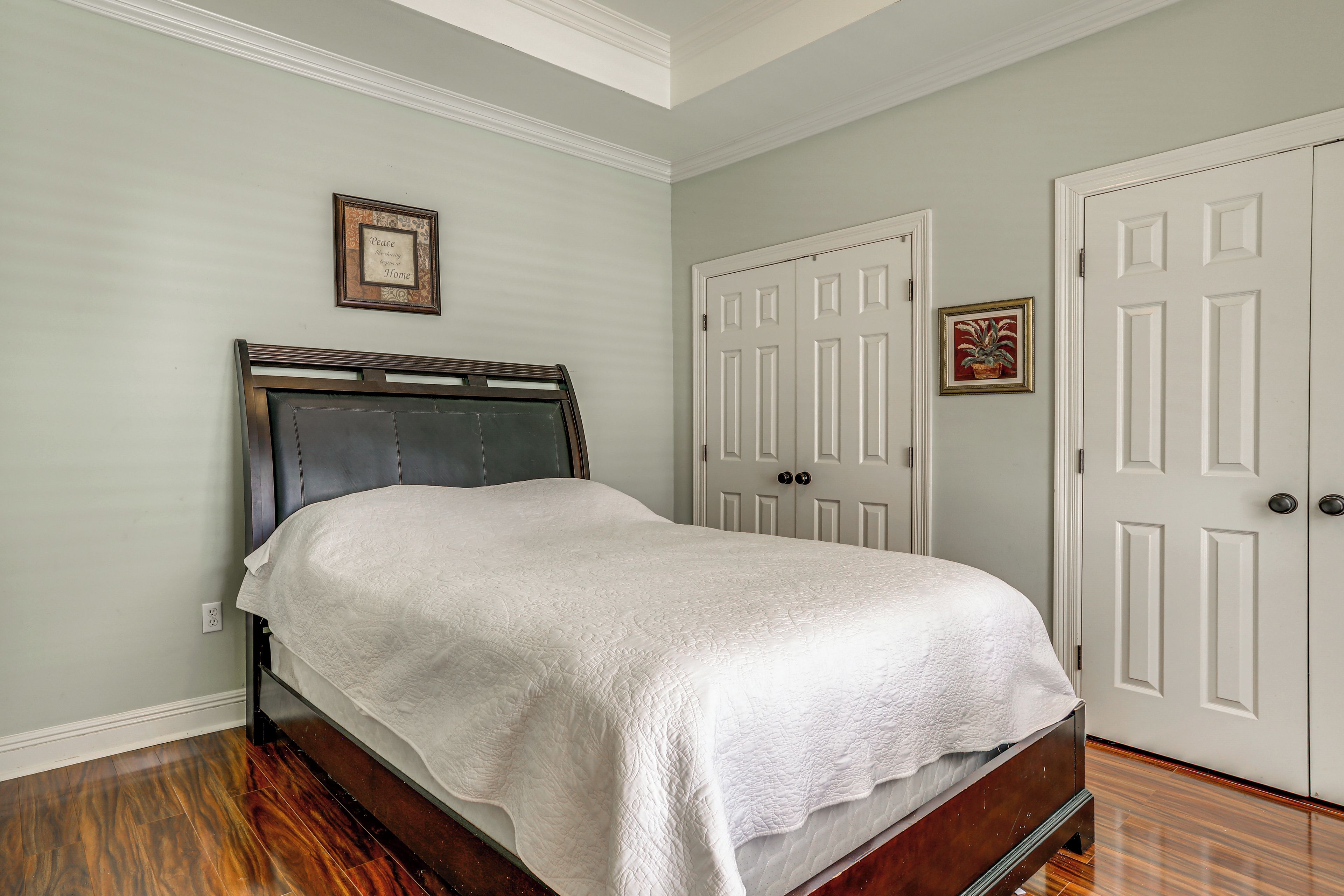 A bedroom with a bed, a door, and a wall-mounted picture frame.