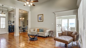 A spacious living room with hardwood flooring, a ceiling fan, a chandelier, and a dining area with a table and chairs. - Easy Access to I-10: Prairieville Extended Stay (Prairieville)