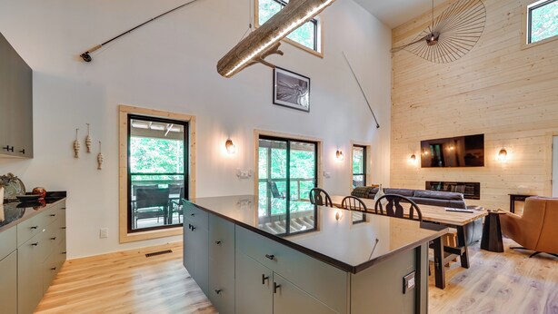Una cocina moderna con una isla central, piso de madera y ventanas amplias.