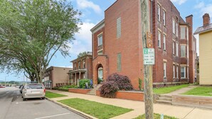A multi-story brick building with a bike trail sign, a parking sign, and a sidewalk with a car parked on the street. - Downtown Apt: 23 Mi to Hocking Hills State Park (Lancaster)