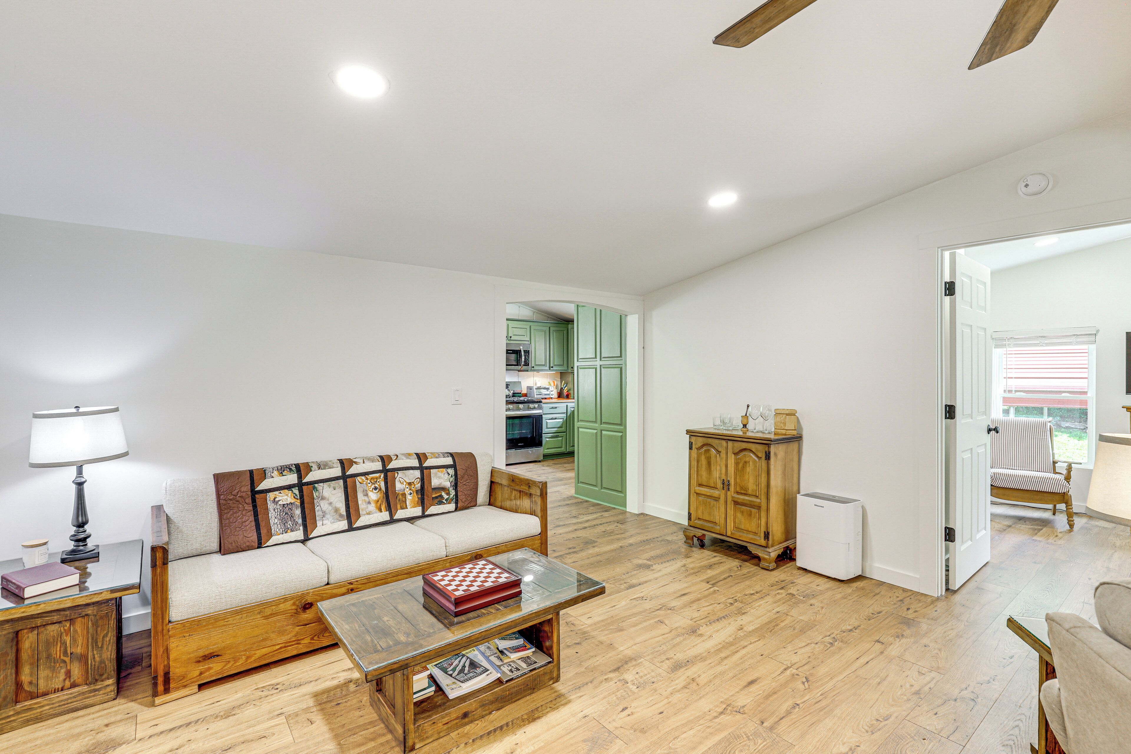 A living room with a sofa, coffee table, and a lamp. There is a wooden cabinet and a radiator.