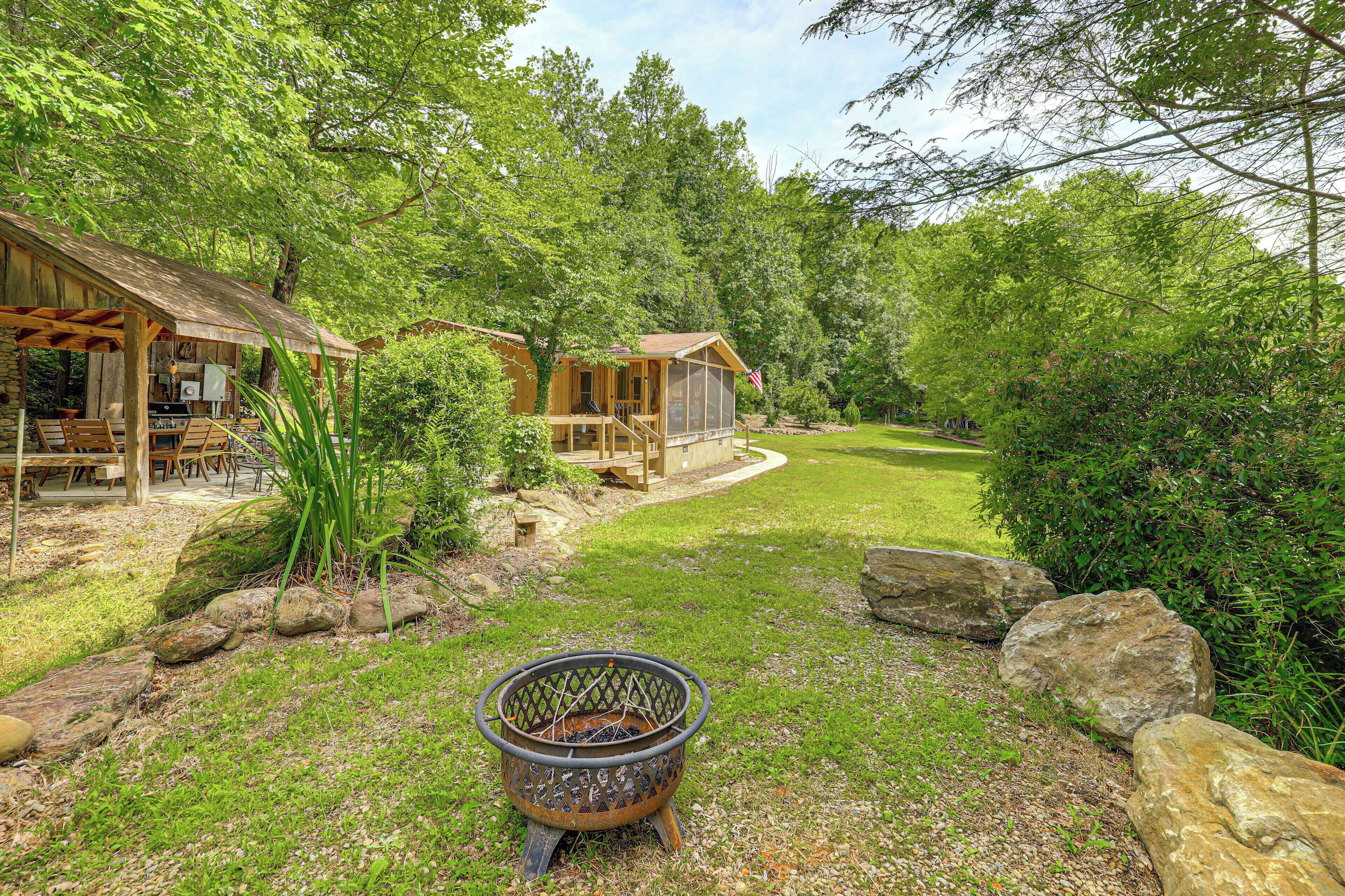 A rustic cabin with a wooden deck, a fire pit, and a well-maintained lawn.