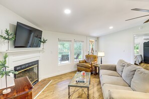 A living room with a fireplace, a sofa, a coffee table, and a TV mounted on the wall. - Serene Cabin w/ Pond & Creek on South Saluda River (Cleveland)