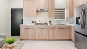 Une cuisine moderne avec des meubles en bois, un réfrigérateur en acier inoxydable et une cuisinière encastrée.