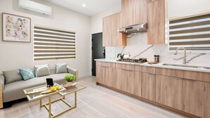 Une cuisine moderne avec des meubles en bois, une cuisinière encastrée et une grande fenêtre équipée de stores.