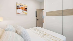 Une chambre à coucher comprenant un lit, des oreillers, une armoire, une porte et une œuvre d’art accrochée au mur.