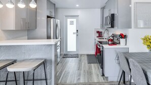 Una cocina moderna con gabinetes grises, electrodomésticos de acero inoxidable y una zona de bar con taburetes.
