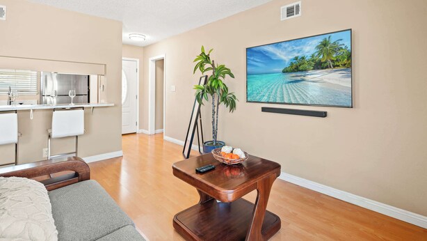 A living room with a wooden coffee table, a potted plant, and a painting of a beach scene. - Cozy Modern 4B Family Retreat House (Ontario)