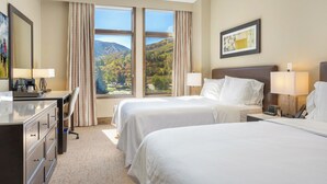A hotel room with two beds, a desk, and a view of mountains. - Riverfront Resort & Spa w Gondola | WR421B (Avon)