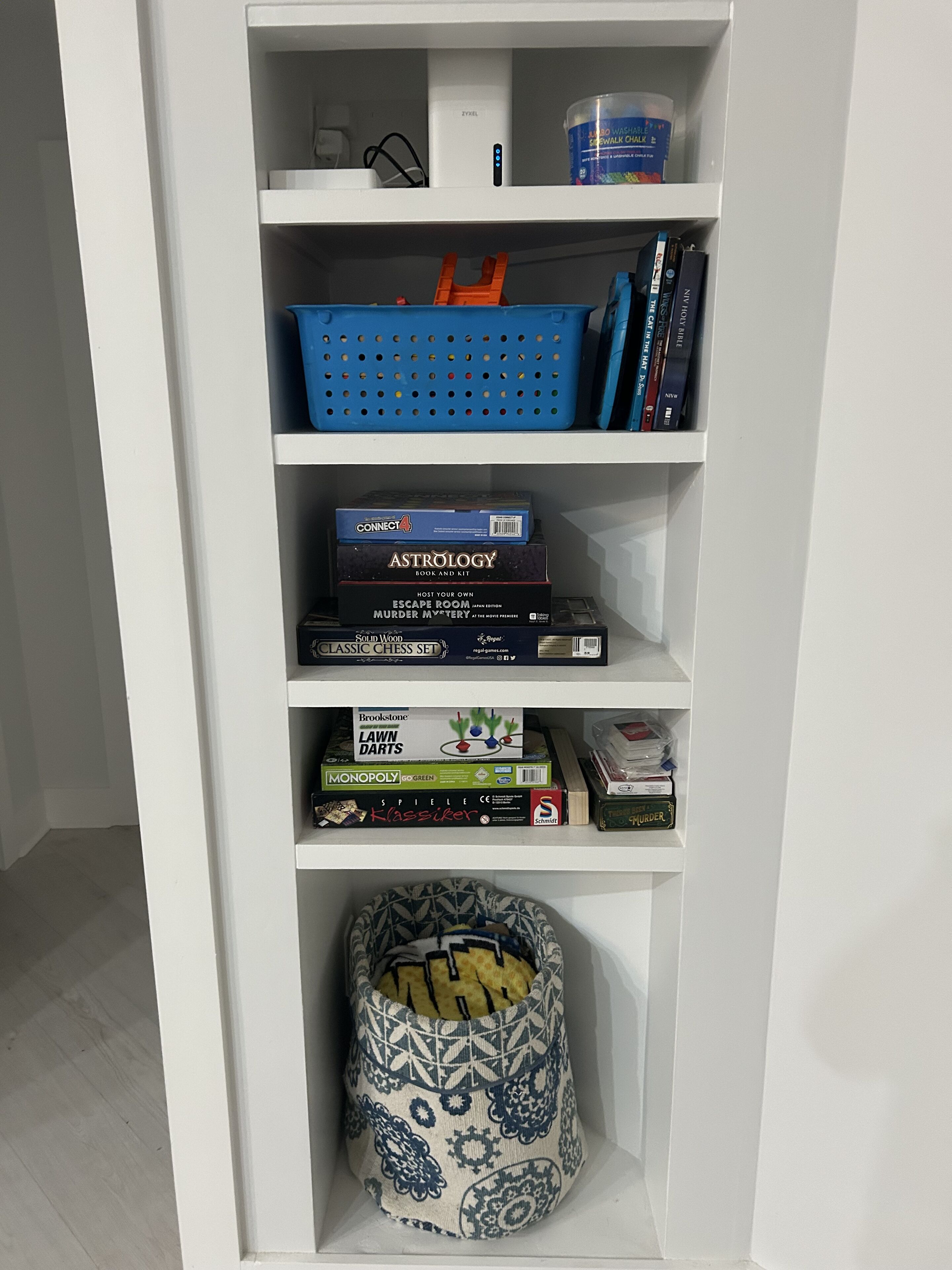 A bookshelf with various board games and a patterned bag.