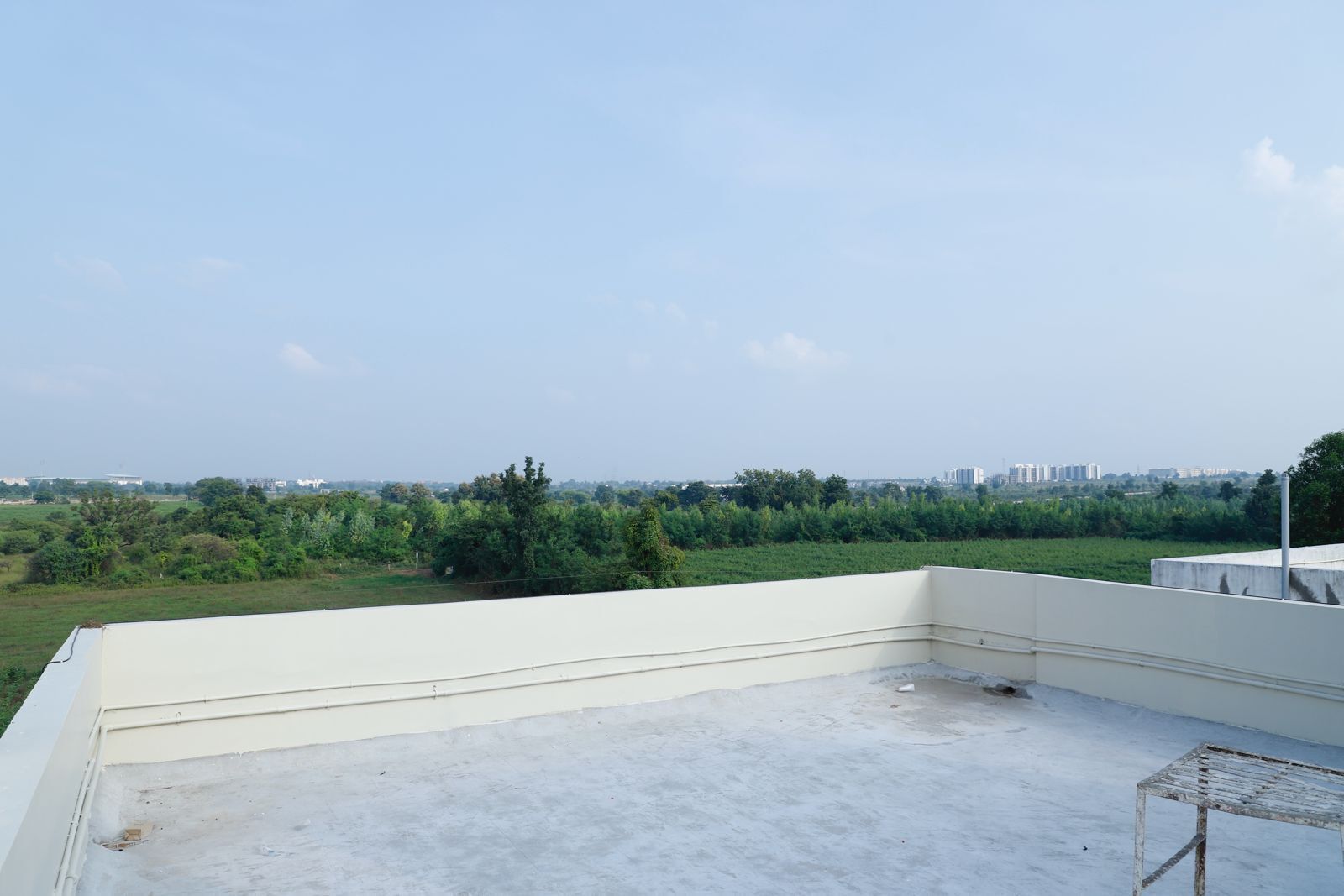 Une terrasse sur le toit offrant une vue dégagée sur un champ verdoyant et des bâtiments éloignés.