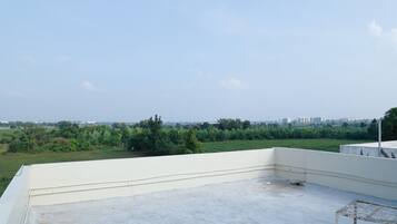 Une terrasse sur le toit offrant une vue dégagée sur un champ verdoyant et des bâtiments éloignés.