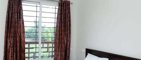 Una camera da letto con un letto, una ventola a soffitto, un condizionatore d'aria e una finestra con tende.