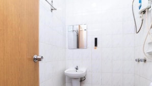 A small, clean bathroom with white tiles, a pedestal sink, a mirror, and a showerhead. - Golden Horse Hotel (Johor Bahru)