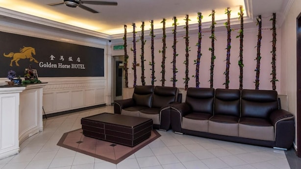 A hotel lobby with a reception desk, a sofa set, a ceiling fan, and a wall with vertical greenery. - Golden Horse Hotel (Johor Bahru)