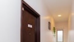 A hallway with a brown door, a small sign, and a window at the end. - Golden Horse Hotel (Johor Bahru)
