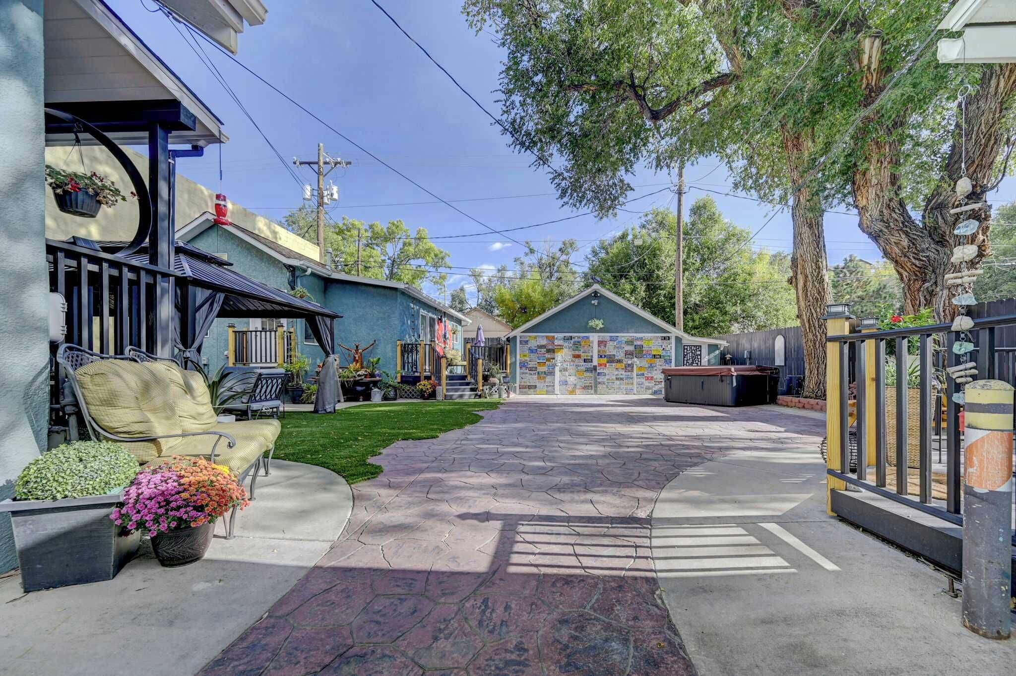 A residential property with a paved driveway, outdoor seating area, and a covered porch.