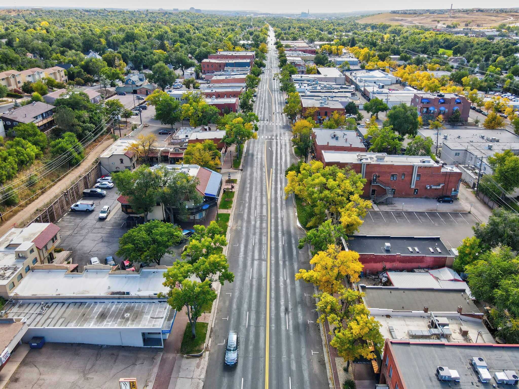 Vista aérea de un pueblo con una calle principal flanqueada por edificios y árboles.