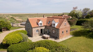 A two-story brick house with a tiled roof, a patio with a table and chairs, and a well-maintained garden. - Drift Cottage, Salthouse, Norfolk (Salthouse)