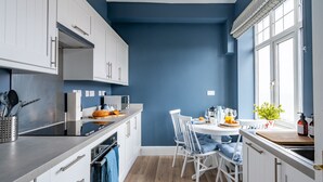 A modern kitchen with white cabinets, a wooden countertop, and a dining area with white chairs. - The Look Out, Sheringham, Norfolk (Sheringham)