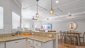 A spacious kitchen with granite countertops, a central island, and a dining area with wooden chairs and a table.