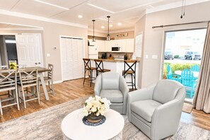 A modern living room with a dining area, kitchen, and a view of the outside. - Updated Destin Beach Walk Condo Quick Beach Access Sandpiper Cove Unit 9102 (Destin)