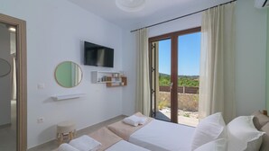 A hotel room with two beds, a TV, a mirror, a small stool, and a view of the outdoors. - Ninalma Villa (Rhodes)