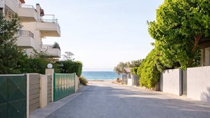 A residential street leading to a beach with a clear view of the sea.