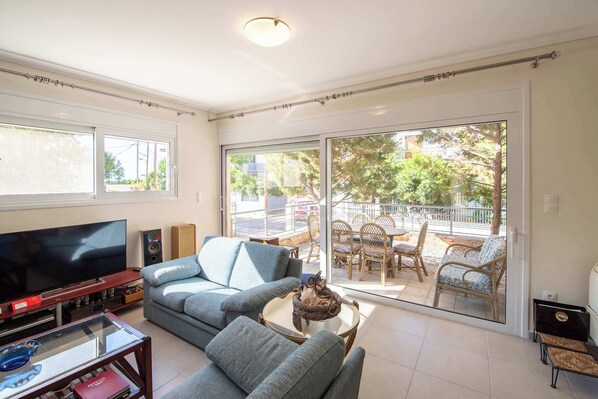 A living room with a TV, sofa, and a glass table.