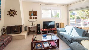 A living room with a sofa, a coffee table, a TV, and a fireplace.