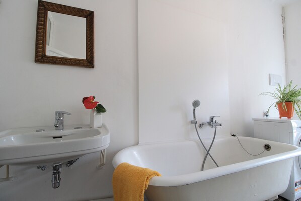 A bathroom with a white sink, a bathtub, and a mirror. - Casa Zaira (Feltre)