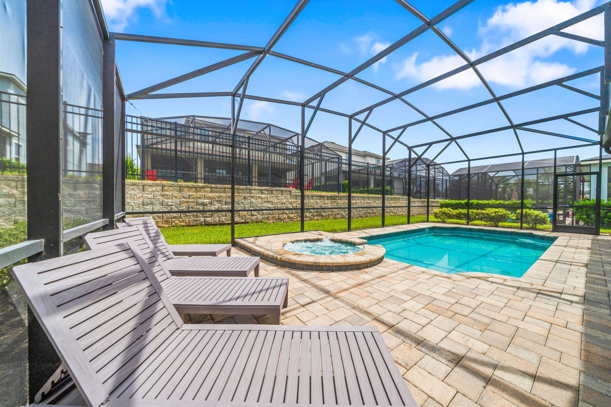 Et overdækket udendørsområde med swimmingpool, liggestole og jacuzzi.