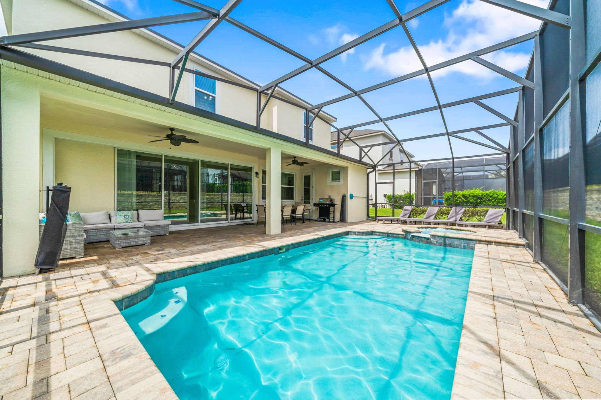 A covered swimming pool with a glass ceiling, outdoor seating, and a patio area.