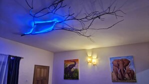 A room with a wooden door, a wall-mounted light fixture, and two paintings of elephants.