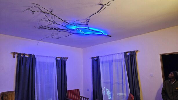 A room with two beds, a wooden chair, a small table, and a ceiling light fixture.