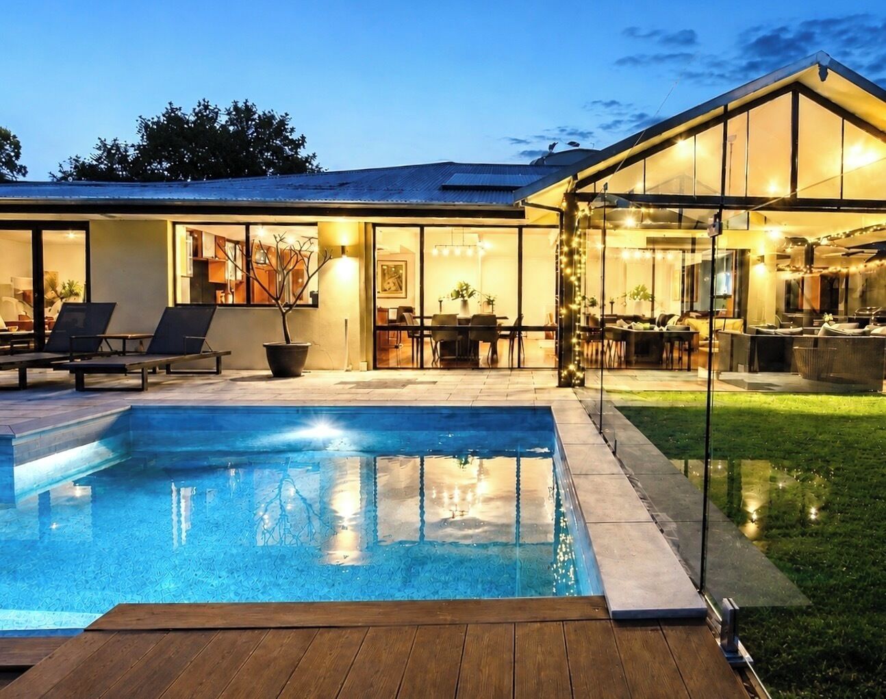 Una casa moderna con piscina, area salotto esterna e patio ben illuminato.