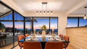 Un espace repas moderne, doté d’une grande table, de chaises et offrant une vue sur le paysage.
