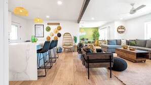 Una sala de estar moderna con un sofá, sillas y una mesa de centro. Hay un comedor con sillas y una mesa.