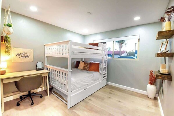 Un dormitorio con una cama litera, un escritorio y una silla.
