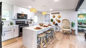 Una cocina moderna con armarios blancos, una isla central con taburetes, un microondas y una estufa.