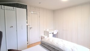 A bedroom with a bed, a desk, and a wardrobe.